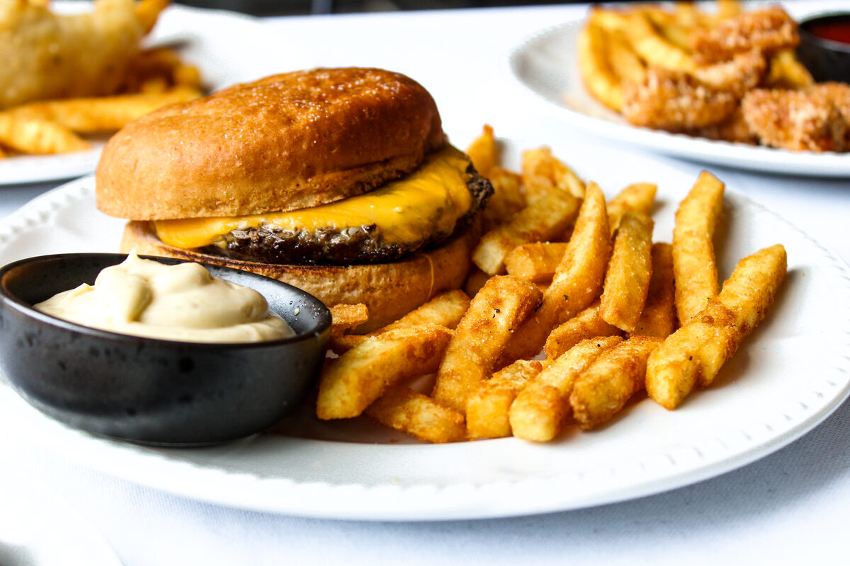 Kids cheeseburger on a gluten free bun with chips and aioli