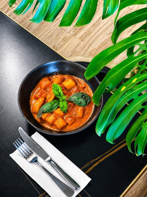 Gluten free gnocchi in creamy coconut tomato sauce topped with fresh basil